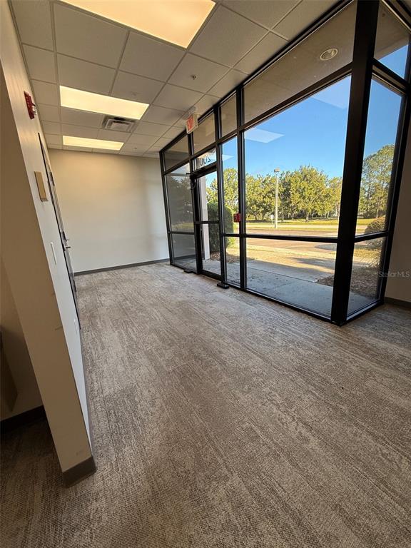 An empty office space features carpeted flooring, a drop ceiling, and large floor-to-ceiling windows — 13859 PROGRESS BOULEVARD UNIT 200, ALACHUA, FL