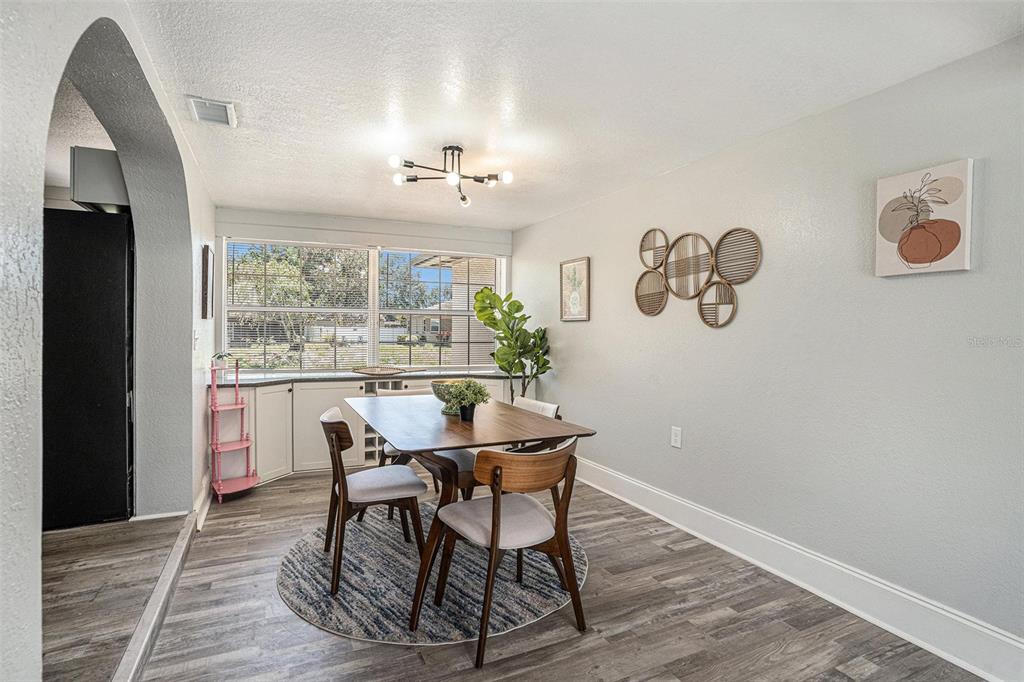 A dining room features a wooden table, mid-century modern chairs, and a large window — 503 PRADO PLACE, LAKELAND, FL