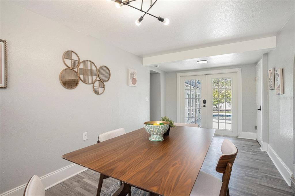 A dining room features a wooden table, modern light fixture, and French doors leading outside — 503 PRADO PLACE, LAKELAND, FL