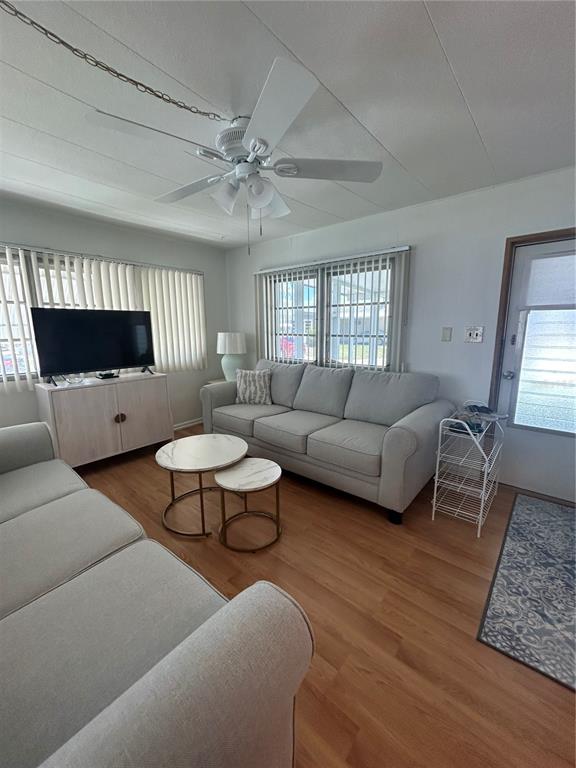 A living room features light-colored sofas, a television on a cabinet, and wood-look flooring — 1874 PALM SPRINGS STREET, SARASOTA, FL