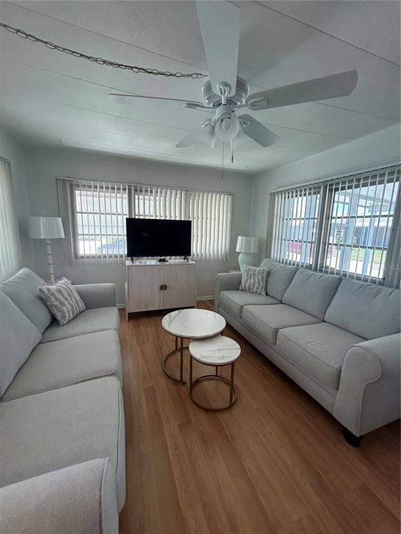 A living room features light gray sofas, a television on a cabinet, and a ceiling fan — 1874 PALM SPRINGS STREET, SARASOTA, FL