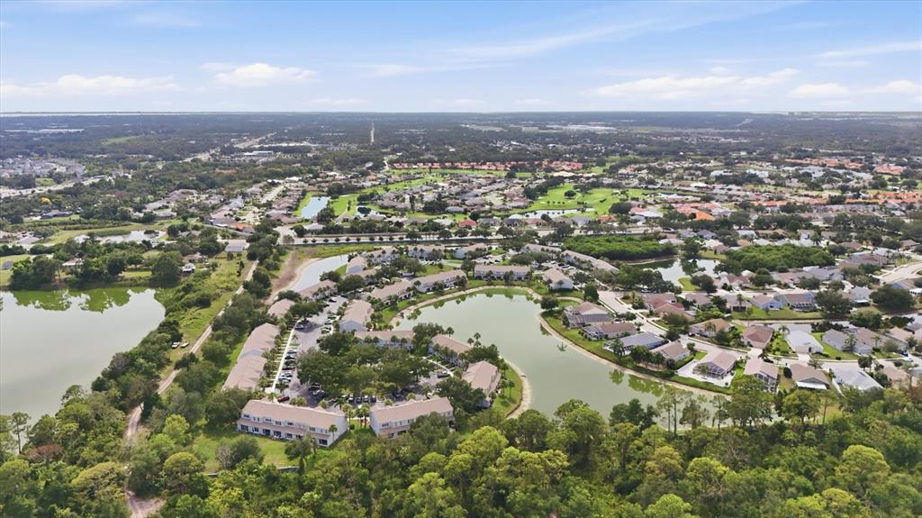 An aerial view shows a residential community with multiple buildings surrounding a central lake — 4642 SABAL KEY DRIVE, BRADENTON, FL