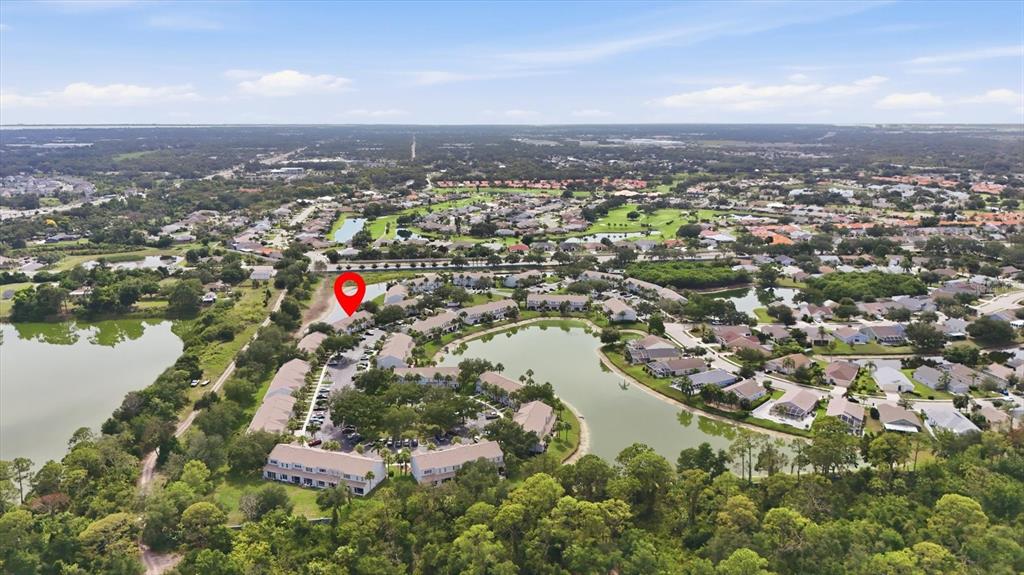 An aerial view shows a residential complex with multiple buildings surrounding a central lake — 4642 SABAL KEY DRIVE, BRADENTON, FL