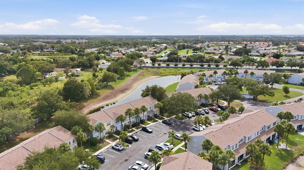 An aerial view shows multi-story townhomes with parking lots and a pond in Florida — 4642 SABAL KEY DRIVE, BRADENTON, FL