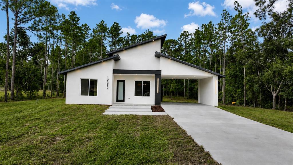 A modern kitchen features matte black cabinetry, wood-accented upper cabinets, and a central island with seating — 12352 SW 61ST PLACE ROAD, OCALA, FL