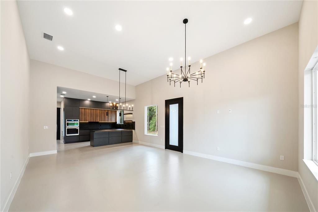 A bright, open-concept living room features a large sectional, woven chairs, and a modern chandelier — 12352 SW 61ST PLACE ROAD, OCALA, FL