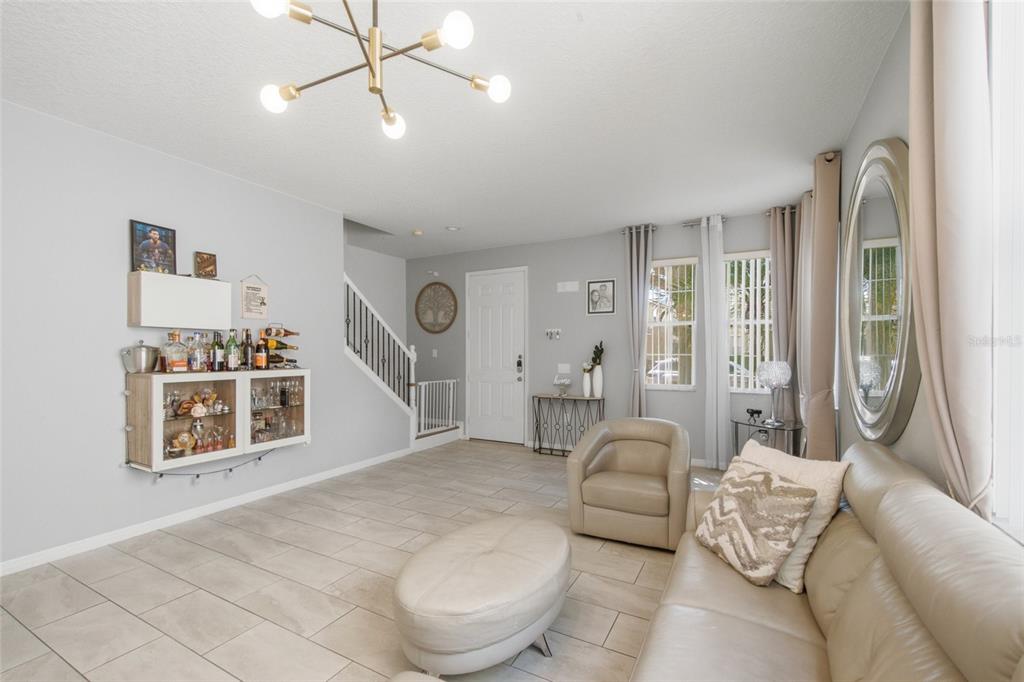 A living room features light tile floors, a modern chandelier, a sofa, and a bar area — 1017 BERKELEY DRIVE, KISSIMMEE, FL