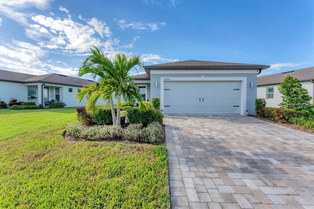 A single-story house with a paved driveway, a two-car garage, and a palm tree — 10661 SPRING TIDE WAY, PARRISH, FL