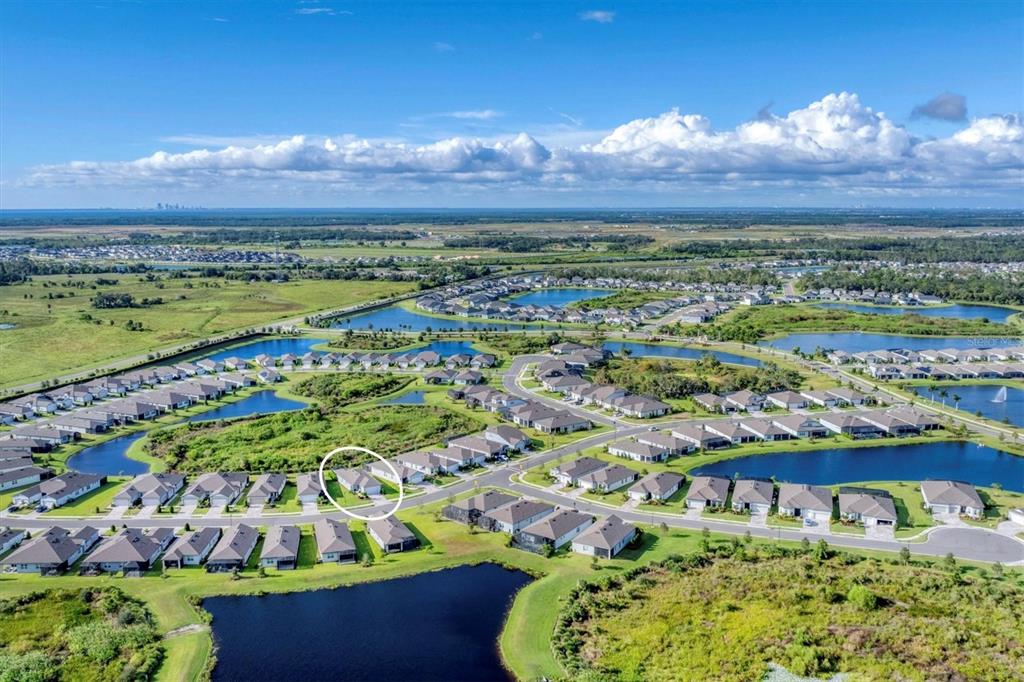 An aerial view of a suburban neighborhood featuring houses, ponds, and green spaces — 10661 SPRING TIDE WAY, PARRISH, FL