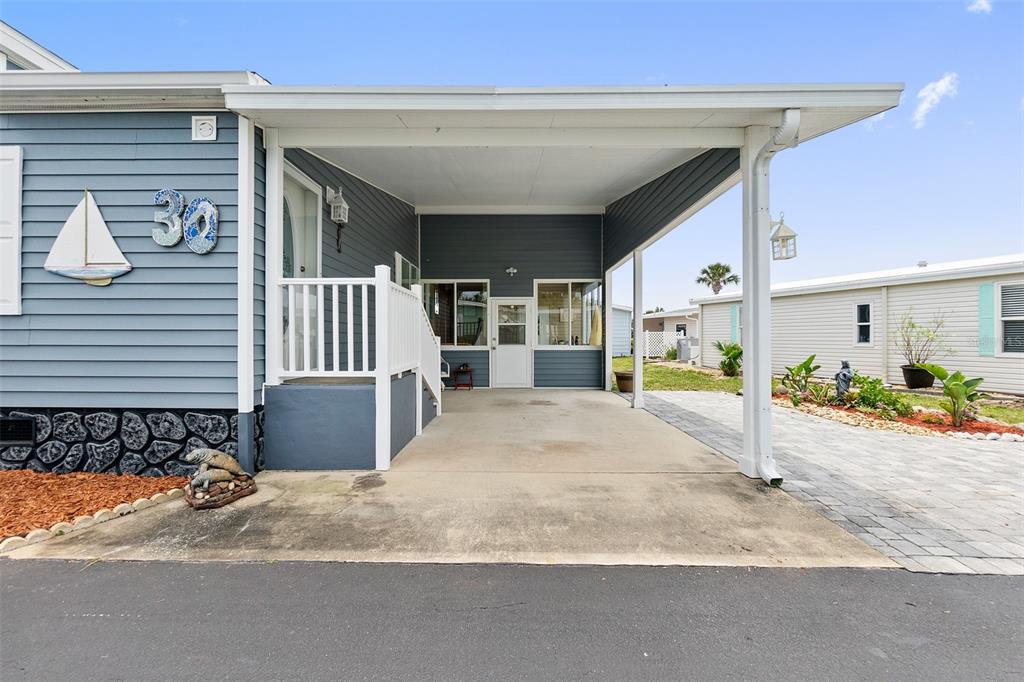 A blue house exterior features a covered carport, a small porch, and a paved driveway — 30 WINDWARD DRIVE, FLAGLER BEACH, FL