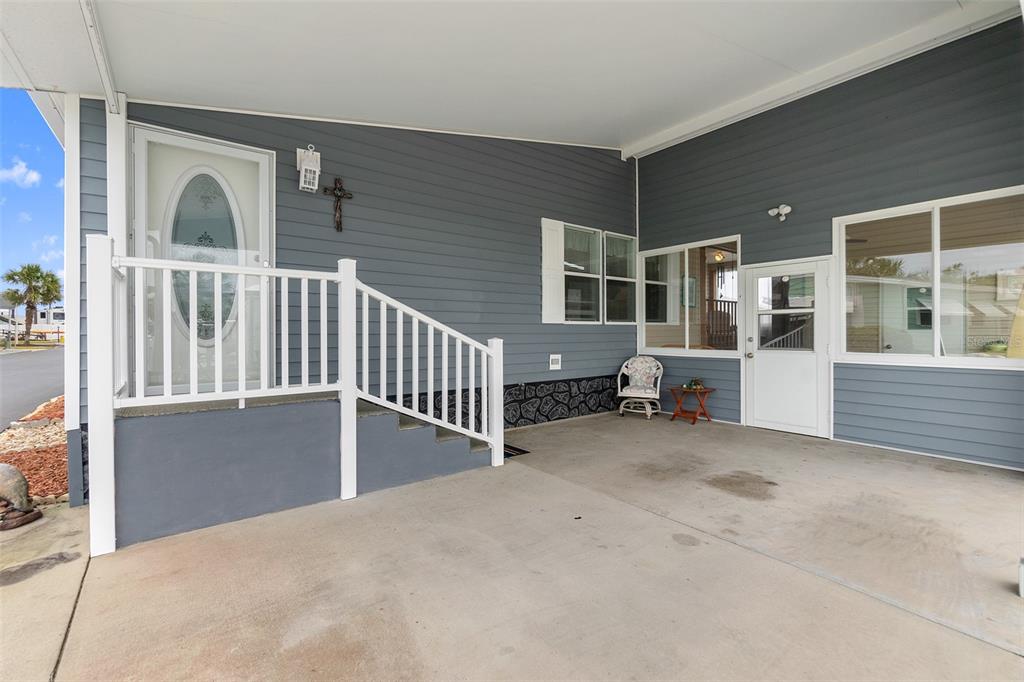 A covered concrete patio features a white railing, stairs, and two exterior doors — 30 WINDWARD DRIVE, FLAGLER BEACH, FL