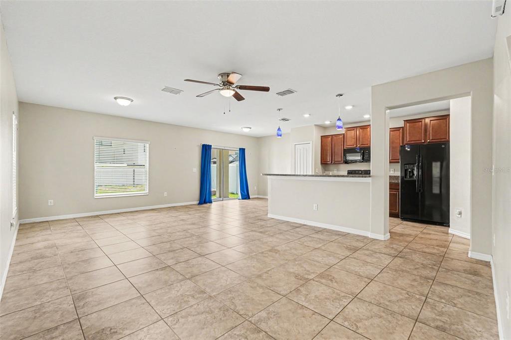 An open-concept living area with tile flooring, a ceiling fan, and an adjacent kitchen — 7421 FRENCH MARIGOLD AVENUE, TAMPA, FL