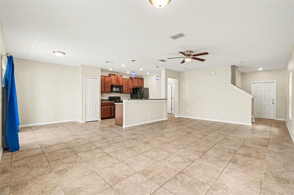 An open-concept living area features tile flooring, a kitchen with dark cabinets, and a staircase — 7421 FRENCH MARIGOLD AVENUE, TAMPA, FL