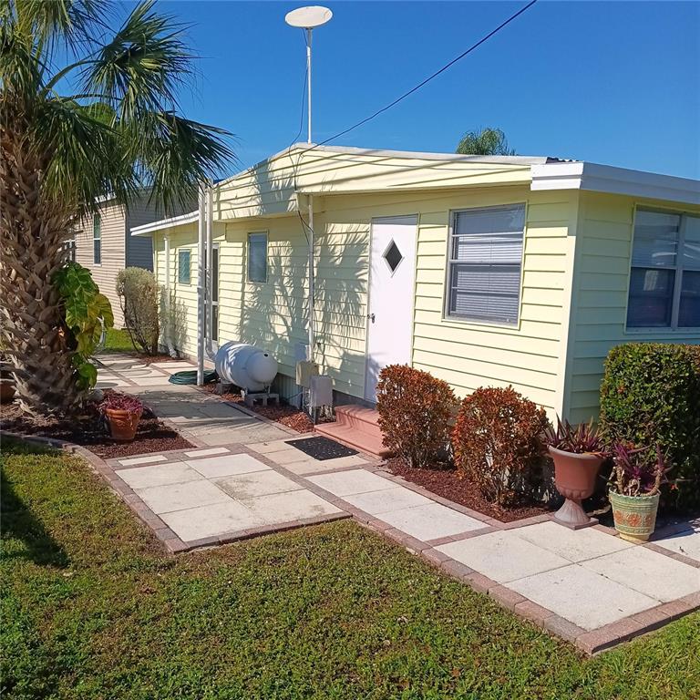 A patio with pavers and a small table sits beside a light-colored house exterior — 810 49TH AVENUE W, BRADENTON, FL