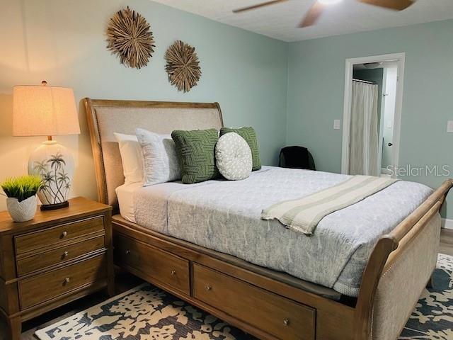 A bedroom features a wooden sleigh bed with storage drawers and a matching nightstand — 4242 HERON WAY UNIT B323, BRADENTON, FL