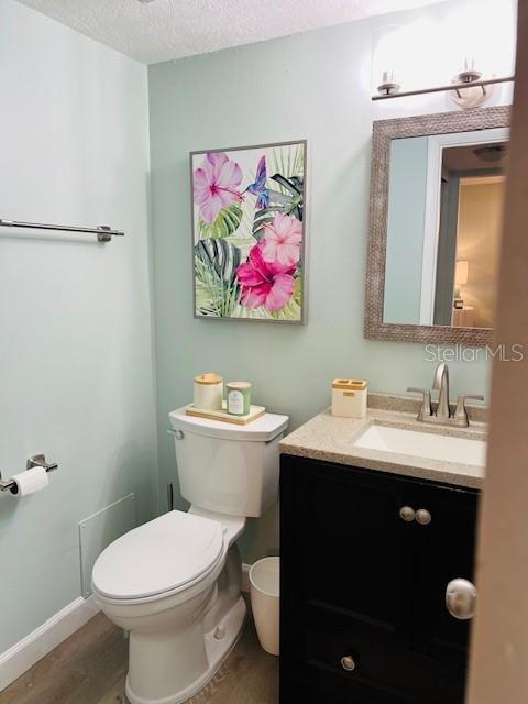 A bathroom features light green walls, a white toilet, a black vanity, and floral wall art — 4242 HERON WAY UNIT B323, BRADENTON, FL