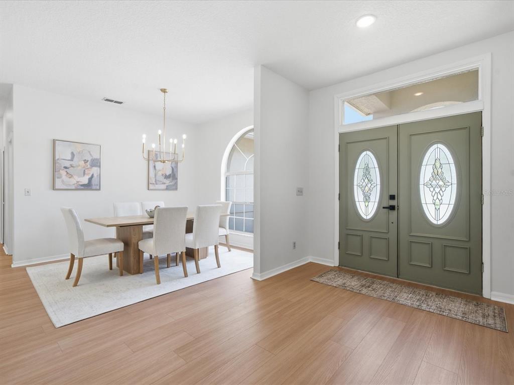 A dining area with a chandelier and table sits beside a green double front door — 4617 DEBBIE LANE, LUTZ, FL