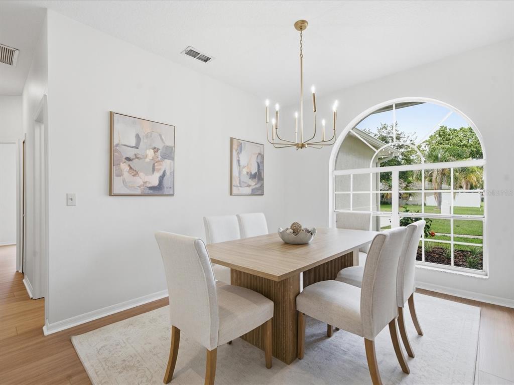 A dining room features a wooden table, six upholstered chairs, a chandelier, and an arched window — 4617 DEBBIE LANE, LUTZ, FL