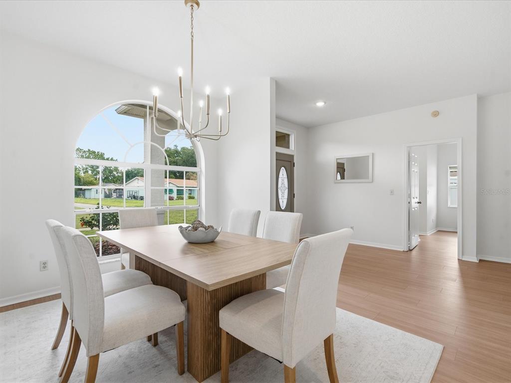 A dining room features a wooden table, six upholstered chairs, and a large arched window — 4617 DEBBIE LANE, LUTZ, FL
