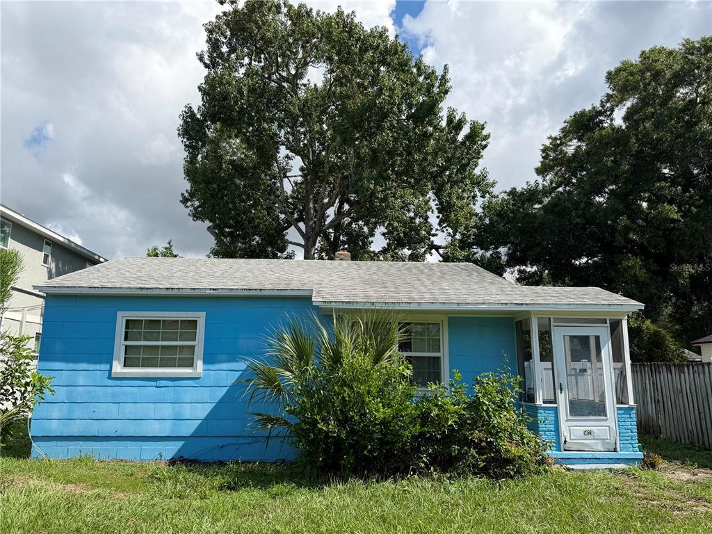 A bright blue, single-story house with a white-trimmed front porch and a large shade tree — 5621 13TH AVENUE S, GULFPORT, FL