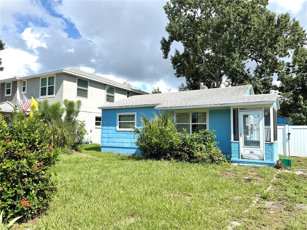 A small, light blue single-story house with a screened front porch sits on a grassy lot — 5621 13TH AVENUE S, GULFPORT, FL