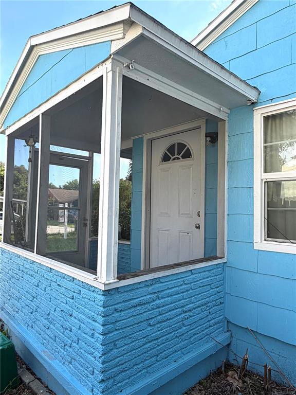 A blue house features a screened-in front porch with a white door and brick base — 5621 13TH AVENUE S, GULFPORT, FL