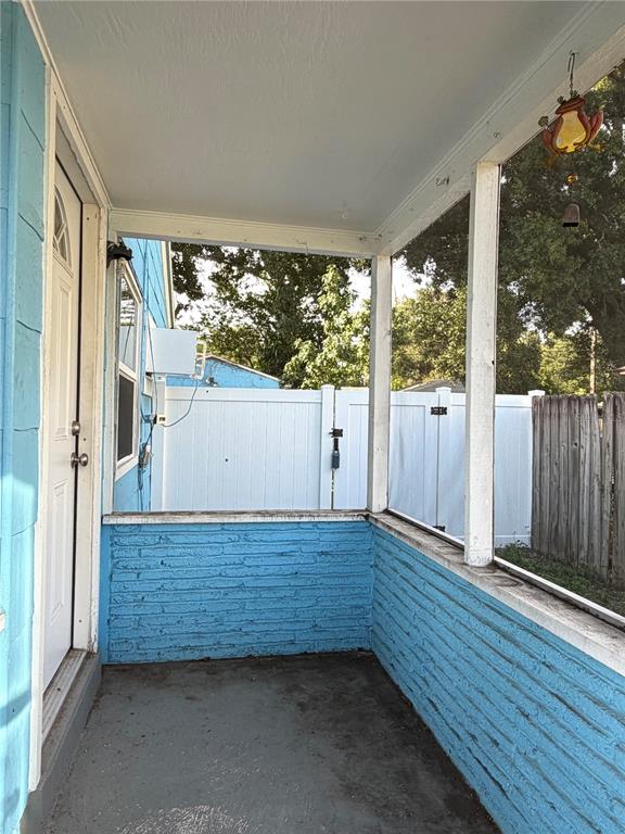 A covered porch features blue painted brick walls, a concrete floor, and a white fence — 5621 13TH AVENUE S, GULFPORT, FL