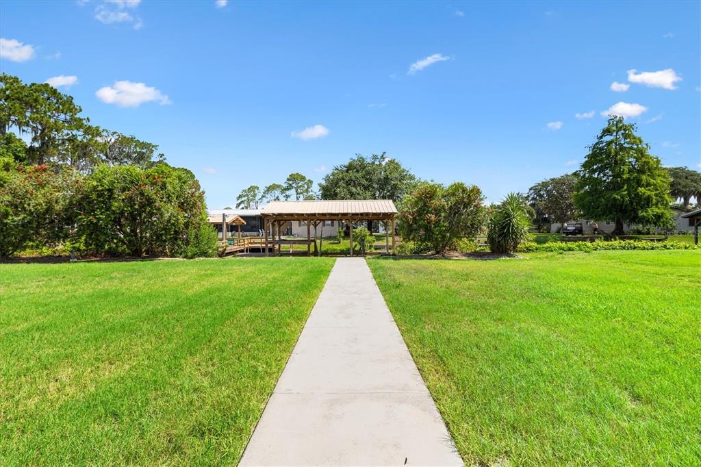 A single-story house with a two-car garage, tan stucco exterior, and a landscaped front yard — 12107 EAGLE POINT COURT, LEESBURG, FL