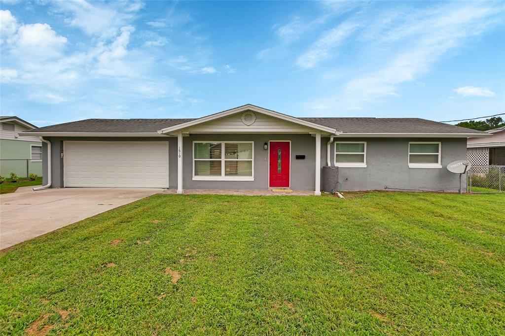 A single-story gray house features a white garage door and a bright red front door — 1610 JUNO TRAIL, ASTOR, FL