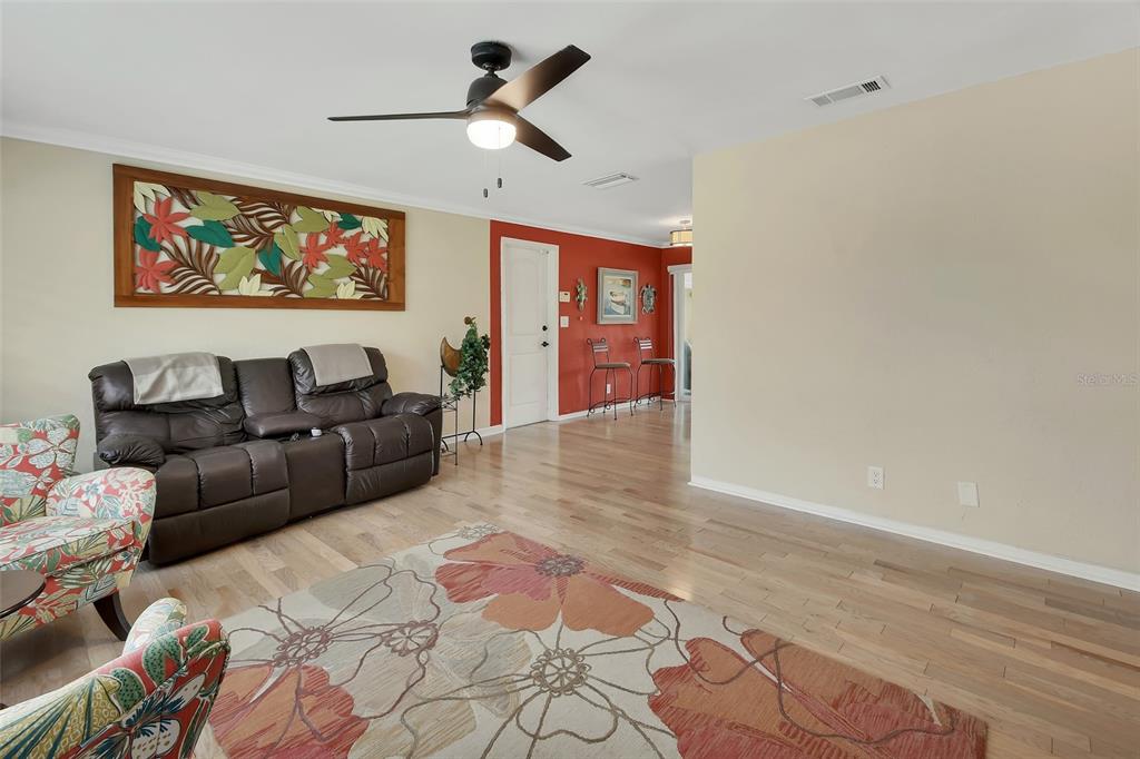 A living room features light hardwood floors, a brown leather sofa, and a floral rug — 1610 JUNO TRAIL, ASTOR, FL