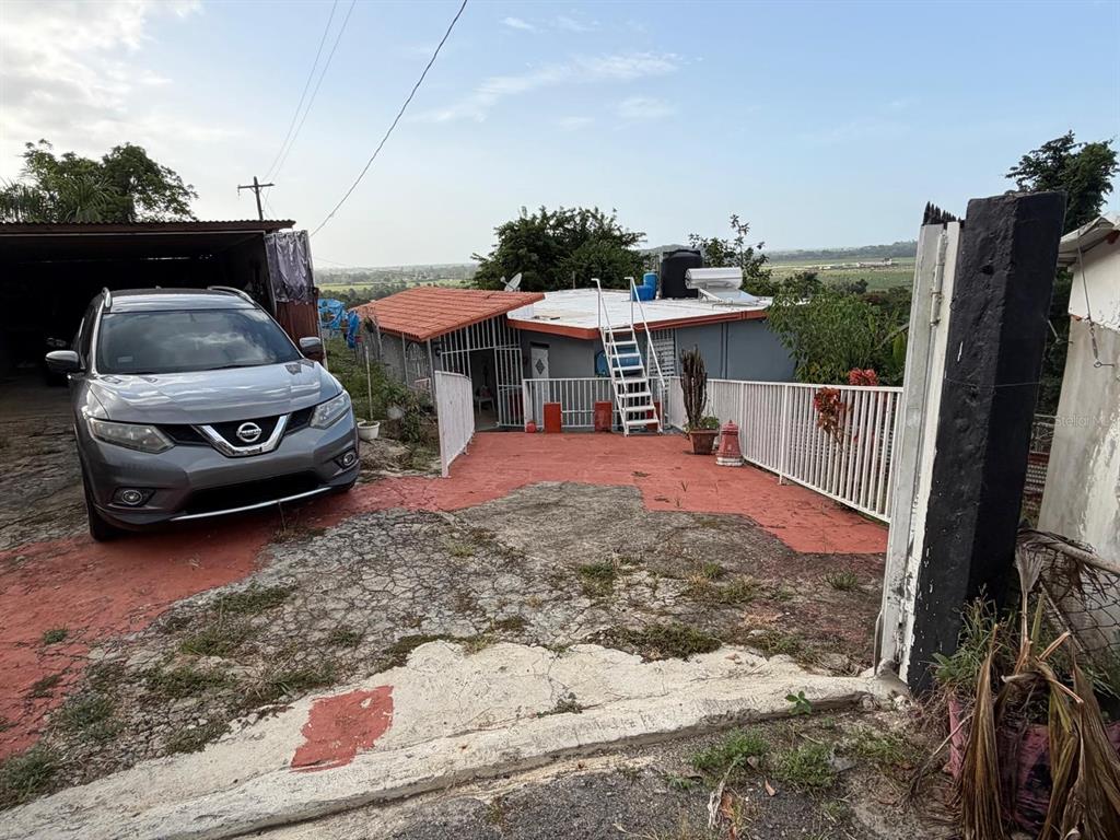 A gray SUV is parked on a driveway in front of a house with a ladder — Carr. 10 BO. HATO VIEJO, ARECIBO, PR