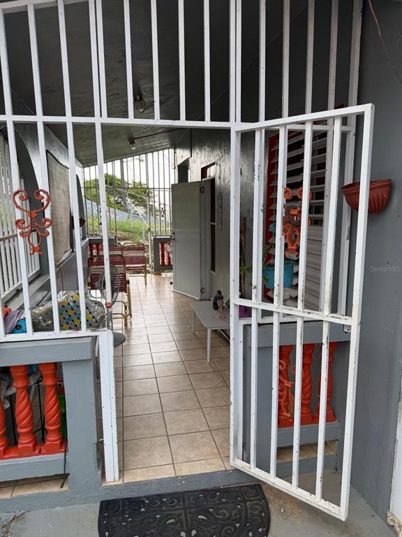 A tiled porch features a white metal security gate, orange balusters, and outdoor furniture — Carr. 10 BO. HATO VIEJO, ARECIBO, PR