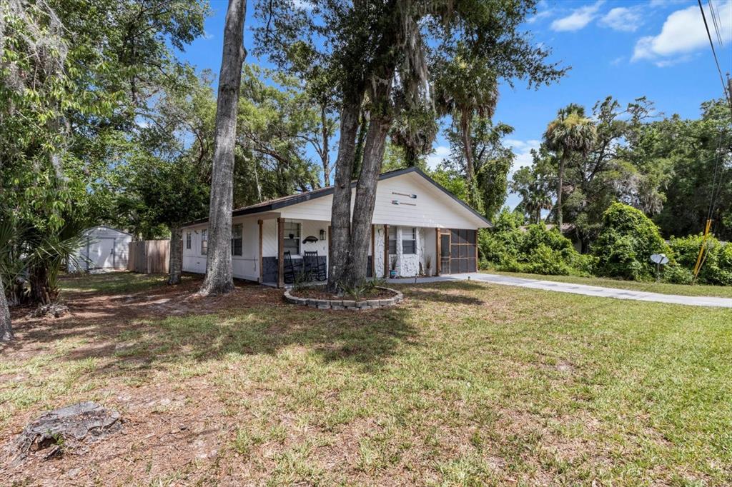 A single-story white house with a screened porch and a large tree in the yard — 4080 N EAGLE NEST POINT, CRYSTAL RIVER, FL