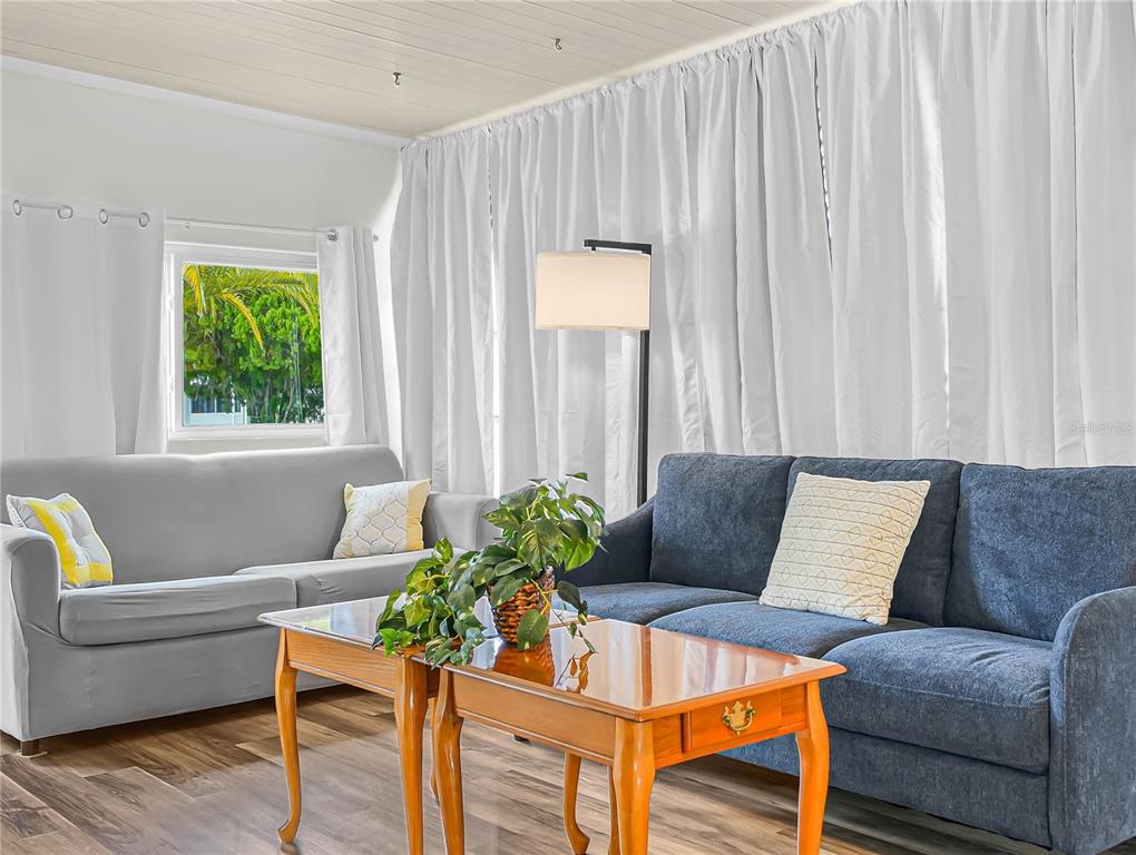 A living room features a grey sofa, a blue sofa, a coffee table, and white curtains — 40 SADDLEBAG TRAIL N, LAKE WALES, FL