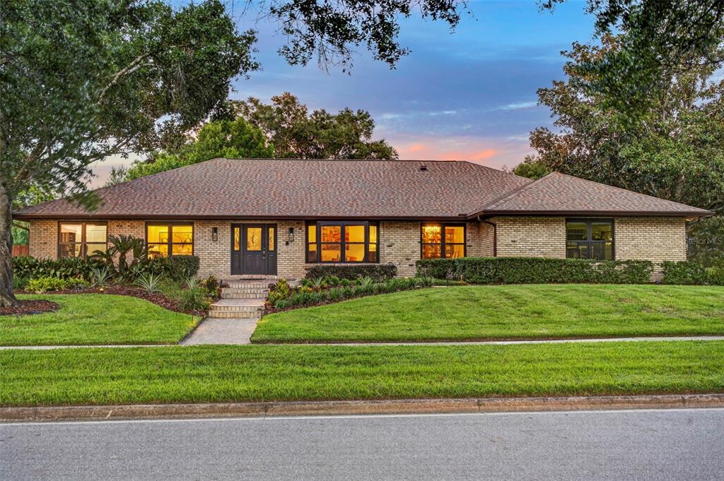 A single-story brick house with a dark front door and a manicured lawn at dusk — 1281 WELLINGTON TERRACE, MAITLAND, FL