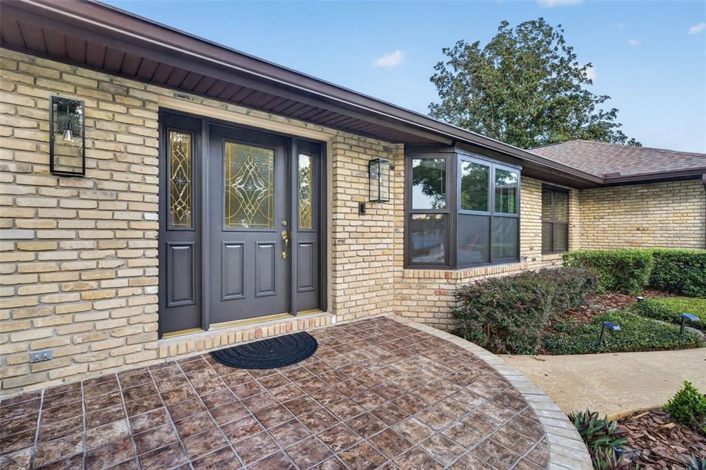 A brick house exterior features a dark gray front door with sidelights and a tiled porch — 1281 WELLINGTON TERRACE, MAITLAND, FL