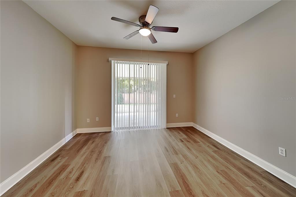 An empty room with light-colored walls, wood-look flooring, a ceiling fan, and vertical blinds — 715 GRAND CANYON DRIVE, VALRICO, FL