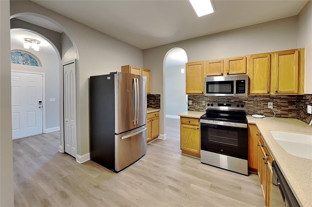 A kitchen with light wood cabinets, stainless steel appliances, and wood-look flooring — 715 GRAND CANYON DRIVE, VALRICO, FL