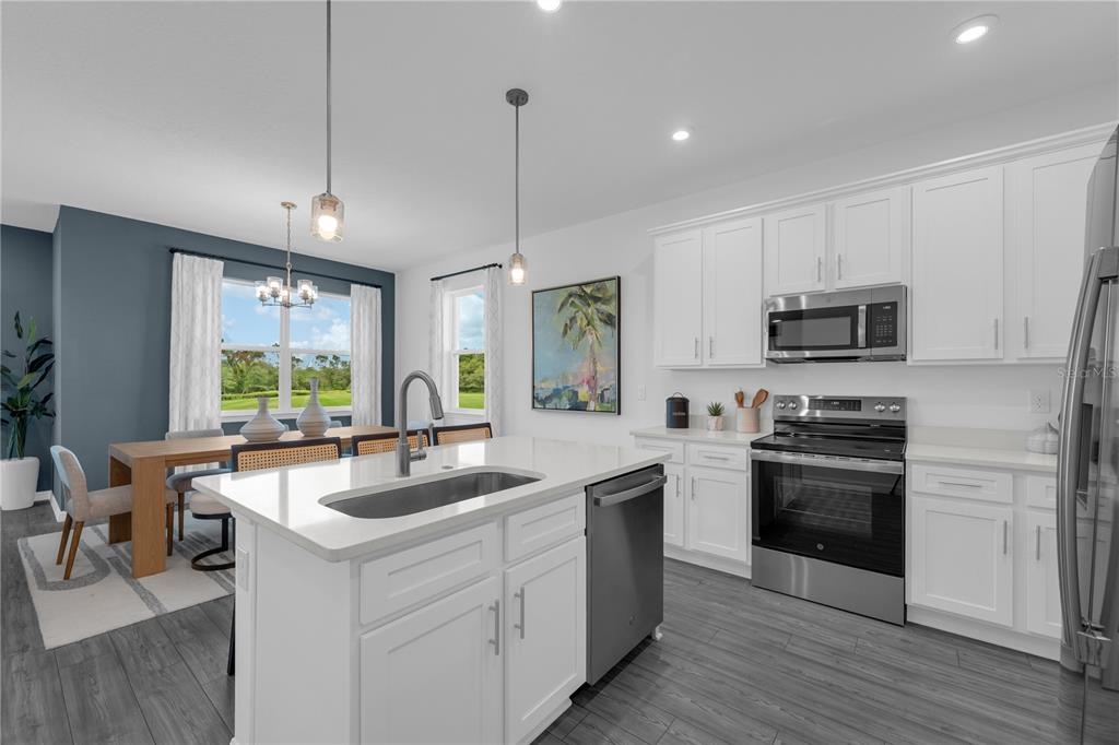 A kitchen with white cabinets, stainless steel appliances, and a central island with a sink — 10067 MORNING MEADOWLARK TRAIL, PARRISH, FL