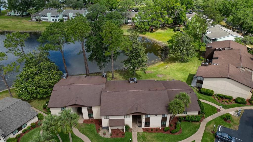An aerial view shows a multi-unit residential building with a brown roof near a pond — 625 MIDWAY DRIVE UNIT A, OCALA, FL