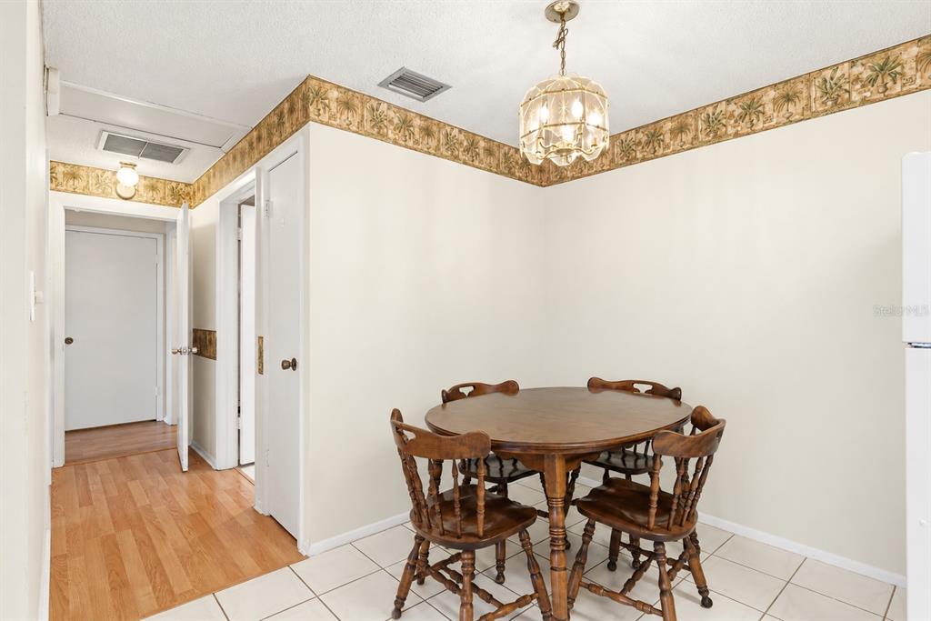 A dining and living area features light blue walls, wood-look flooring, and a kitchen pass-through — 4344 TAHITIAN GARDENS CIRCLE UNIT B, HOLIDAY, FL