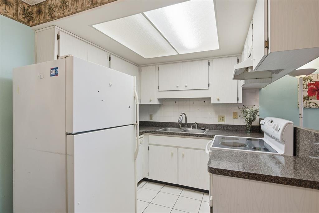 A living room with wood flooring and a large entertainment center opens to a dining area — 4344 TAHITIAN GARDENS CIRCLE UNIT B, HOLIDAY, FL