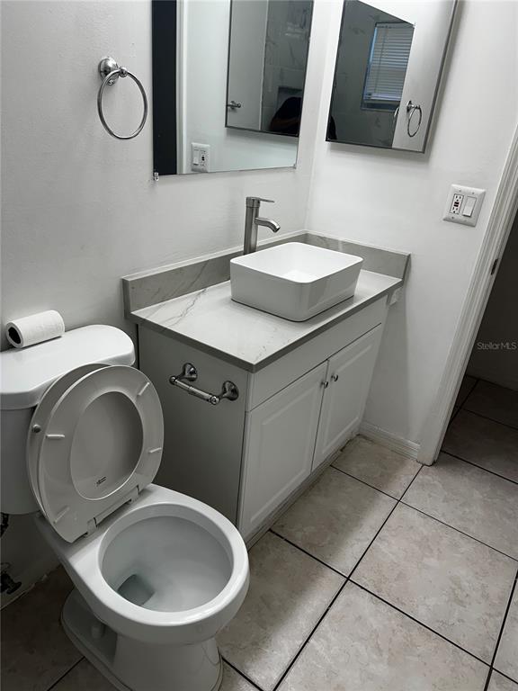 A bathroom features a white vessel sink on a gray vanity, a toilet, and mirrors — 1424 CHESTERFIELD DRIVE, DUNEDIN, FL