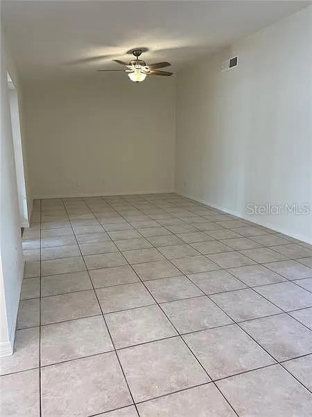 An empty room features light-colored tile flooring, white walls, and a ceiling fan — 1424 CHESTERFIELD DRIVE, DUNEDIN, FL