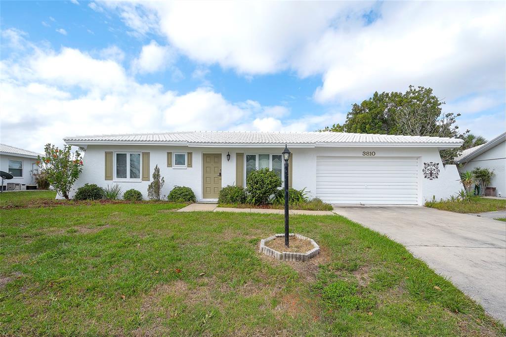 A single-story white house with a garage and a front lawn under a blue sky — 3810 JOYCE DRIVE, BRADENTON, FL