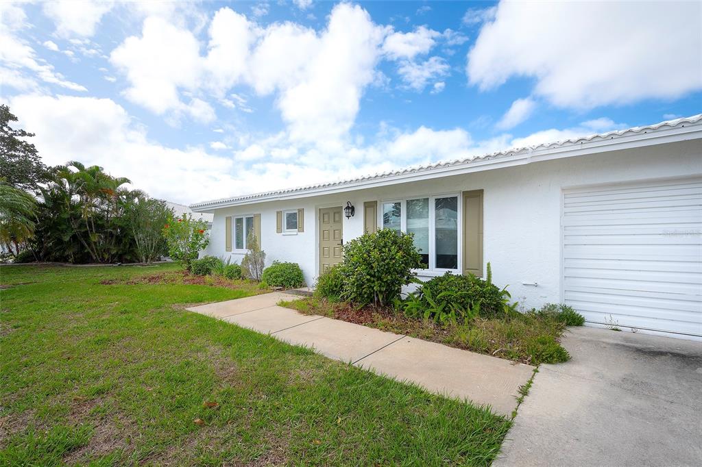 A white single-story house features a concrete walkway, a garage, and a landscaped front yard — 3810 JOYCE DRIVE, BRADENTON, FL