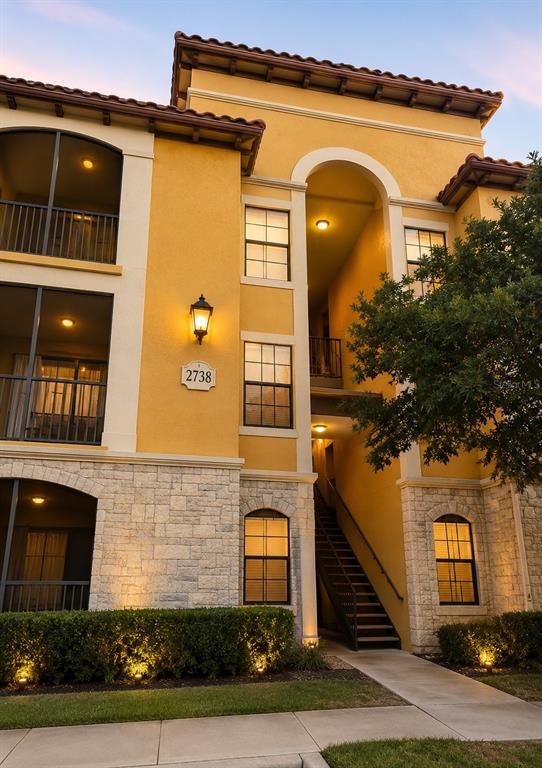 A multi-story apartment building exterior features yellow stucco walls, stone veneer, and a staircase — 6157 METROWEST BOULEVARD UNIT 308, ORLANDO, FL