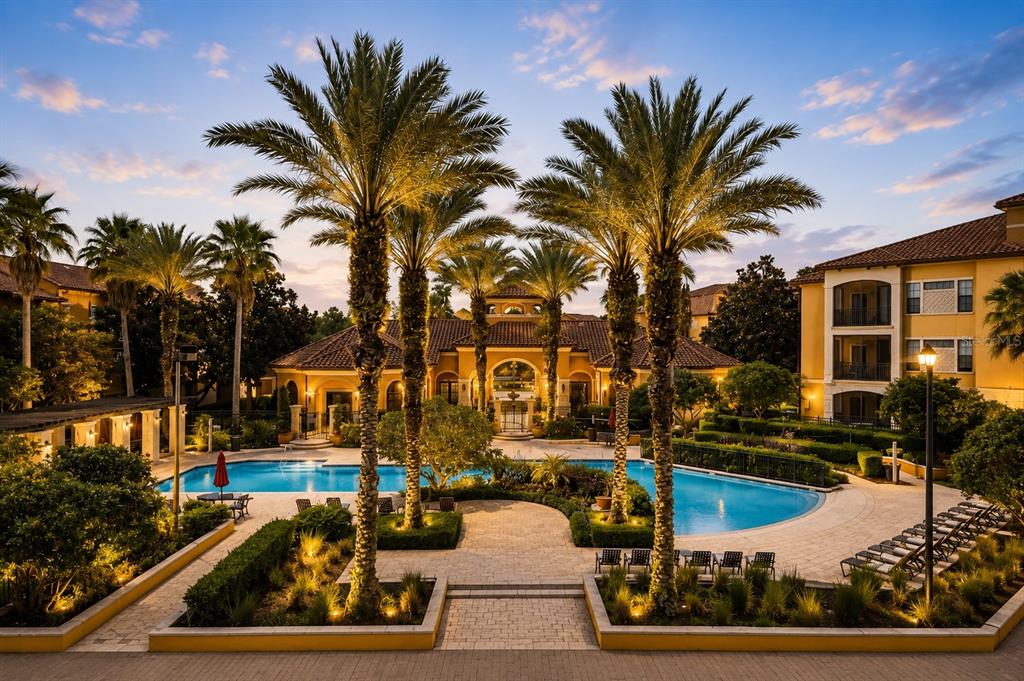 An outdoor swimming pool area with palm trees and a clubhouse at sunset — 6157 METROWEST BOULEVARD UNIT 308, ORLANDO, FL