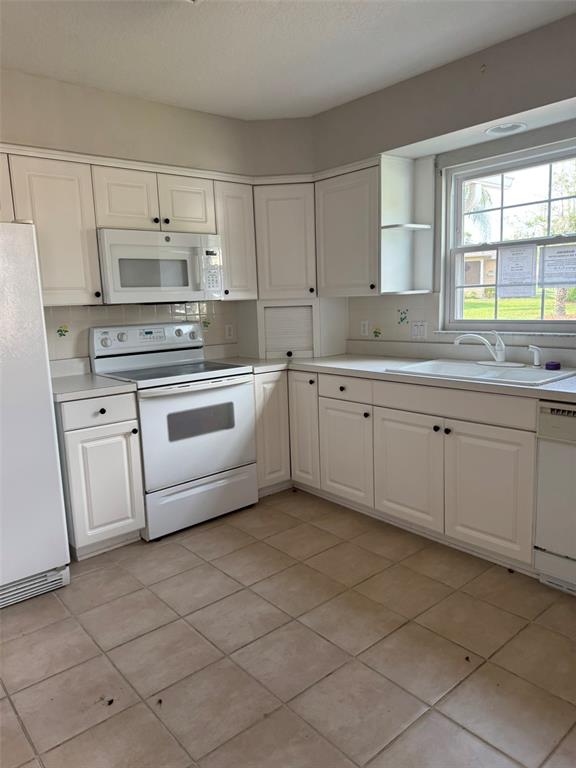 An entryway with tile flooring leads into a living area featuring wood-look laminate floors — 37414 CASTLEBERRY DRIVE, ZEPHYRHILLS, FL