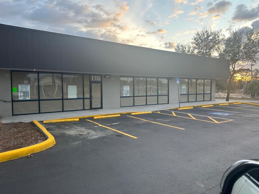 A commercial building exterior features a gray facade, large glass windows, and a parking lot — 1727 E BUSCH BOULEVARD, TAMPA, FL